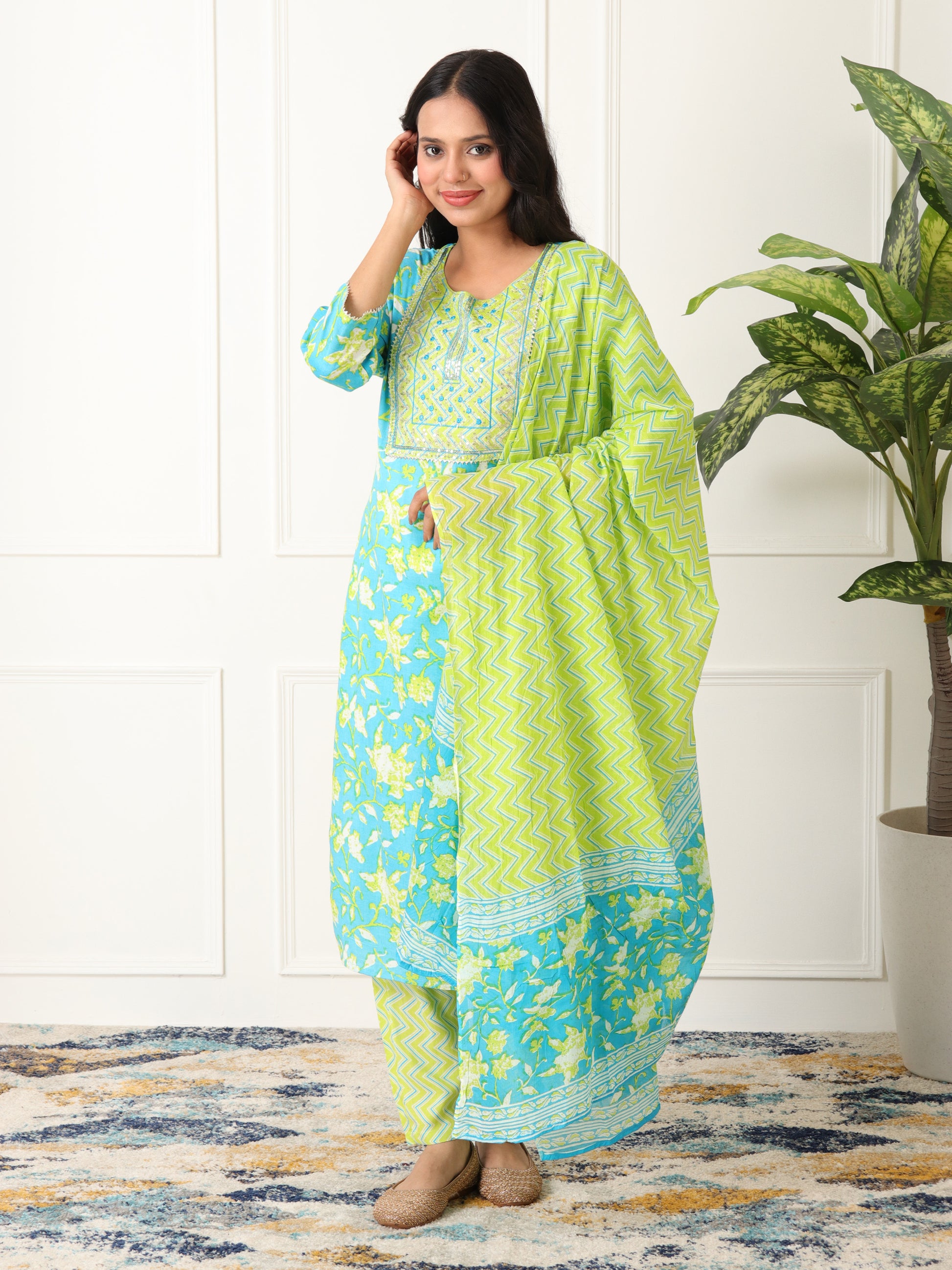 Woman wearing a green and blue traditional outfit with a plant in the background kurti set for women under Rs. 999