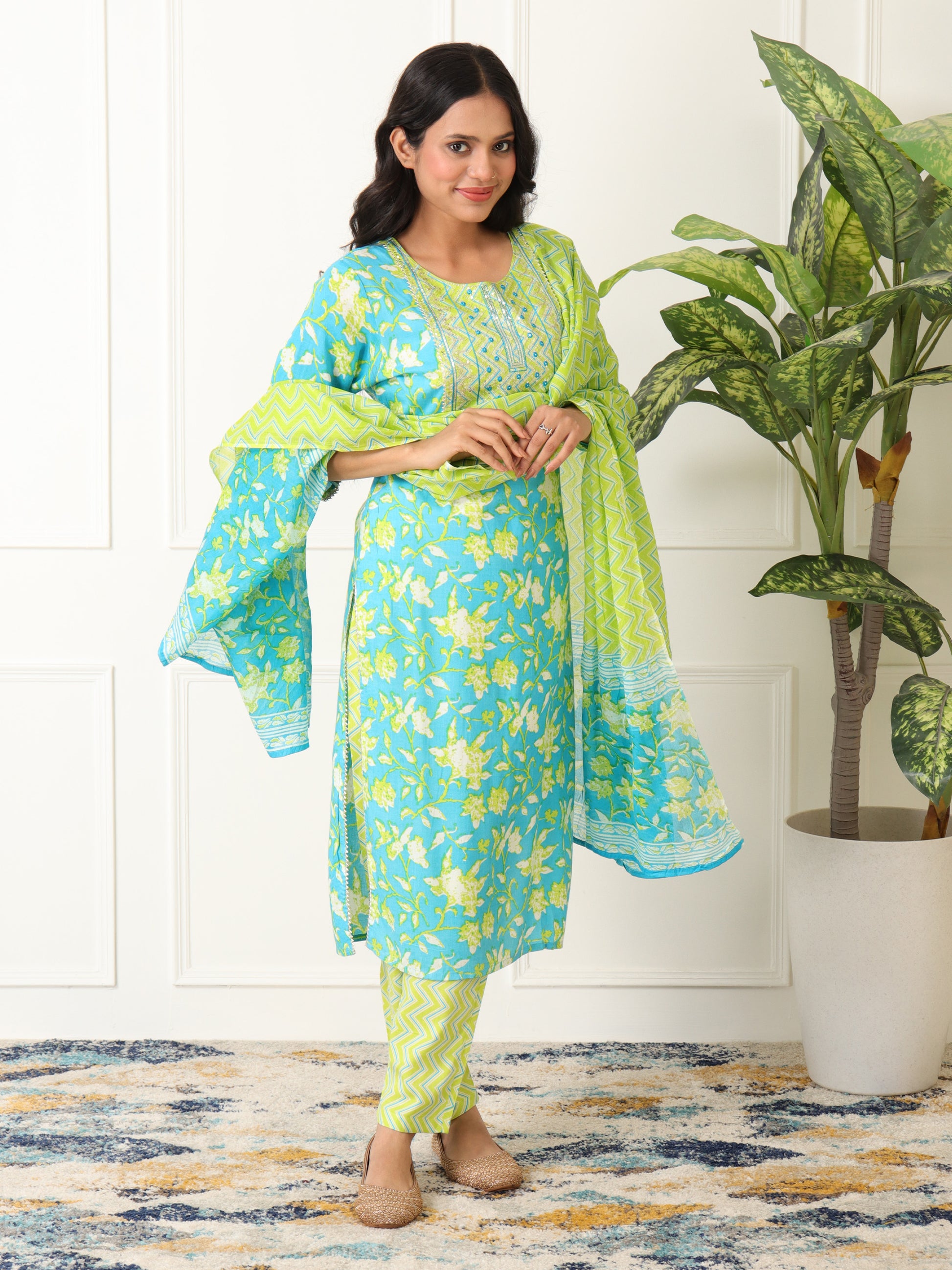 Woman wearing a turquoise and green traditional outfit with a plant in the background kurti set for women under Rs. 999